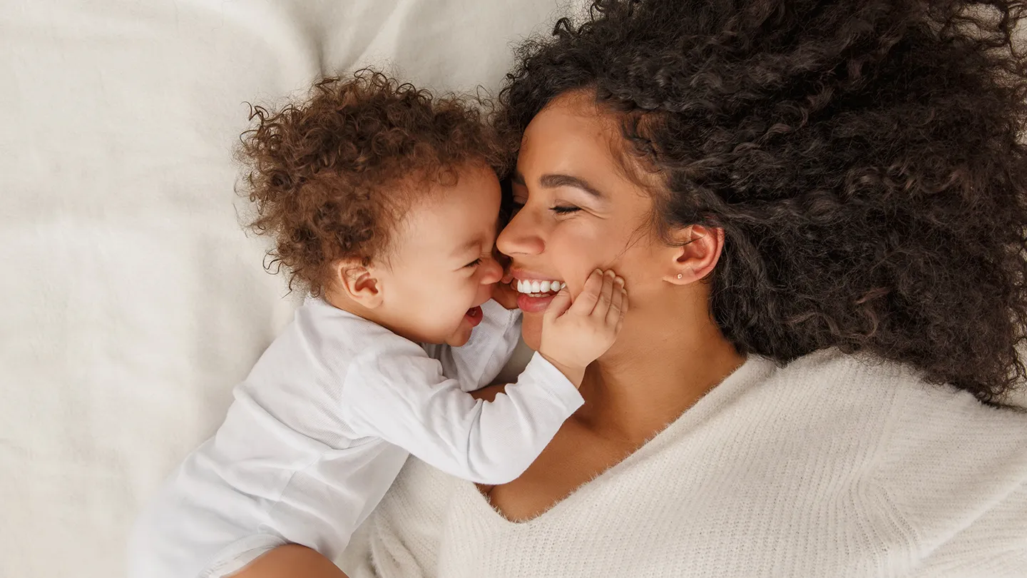 mother and baby smiling together in bed