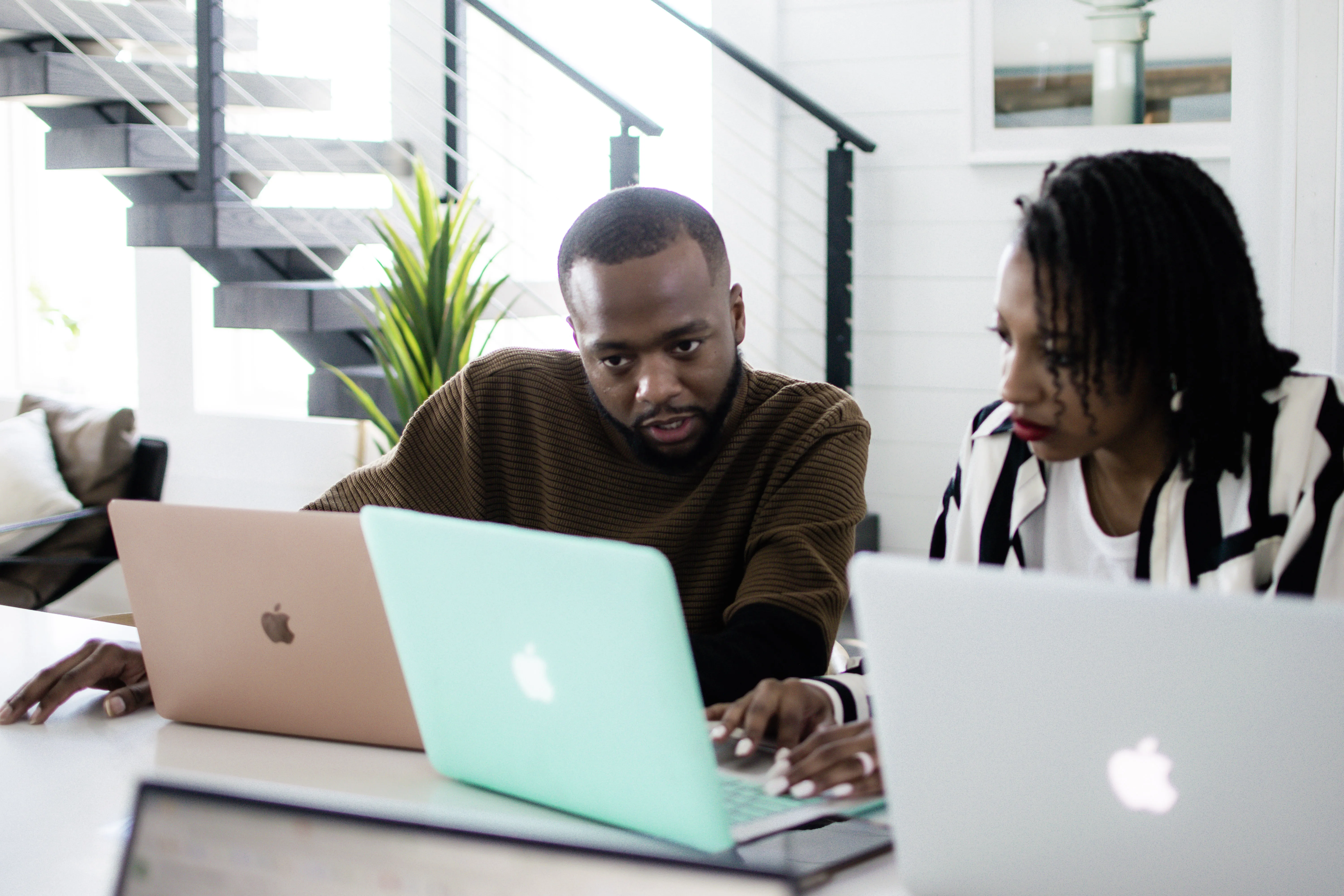 Two Black leaders discussing a project with laptops