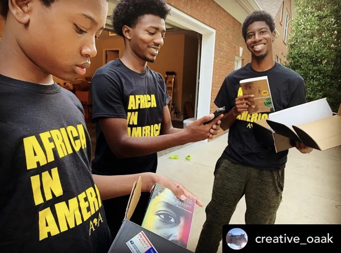 African-American boys pulling books out of box